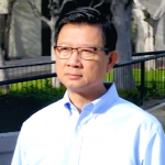 Andrew Do wearing glasses and a light blue collared shirt on a bright sunny day