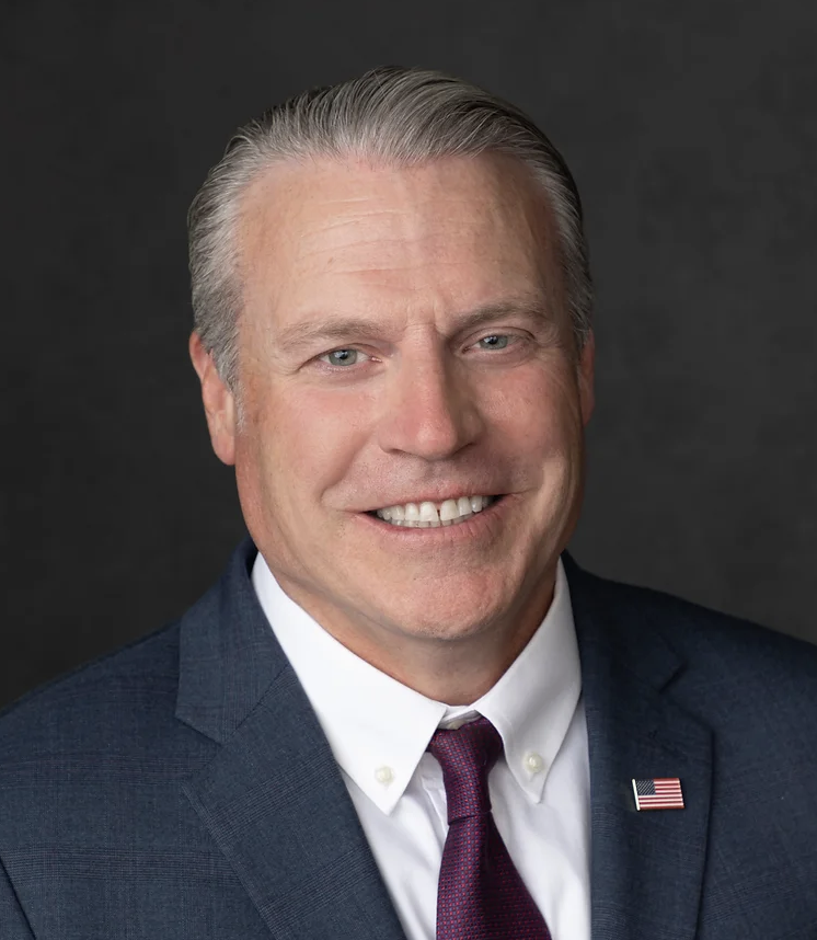 Headshot of Brian Erickson in a business suit with USA flag pin