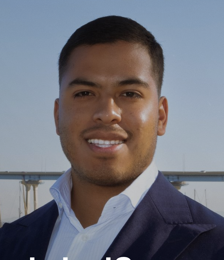 Picture of Japhet Perez Estrada smiling in a navy blue business jacket and open white collared shirt against the Coronado Bridge skyline